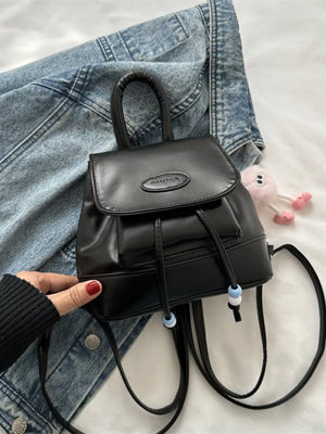 Black leather mini drawstring backpack with beaded accents and top handle.