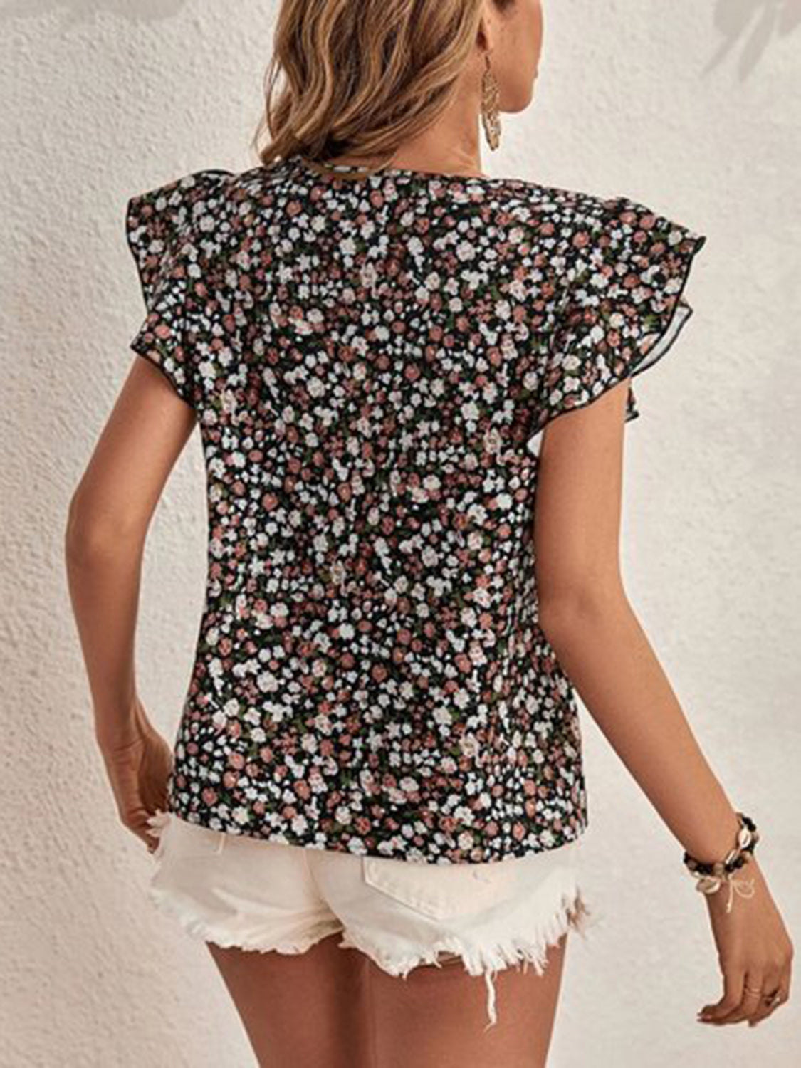 Black floral flutter sleeve blouse with a v-neckline and ruffled sleeves.