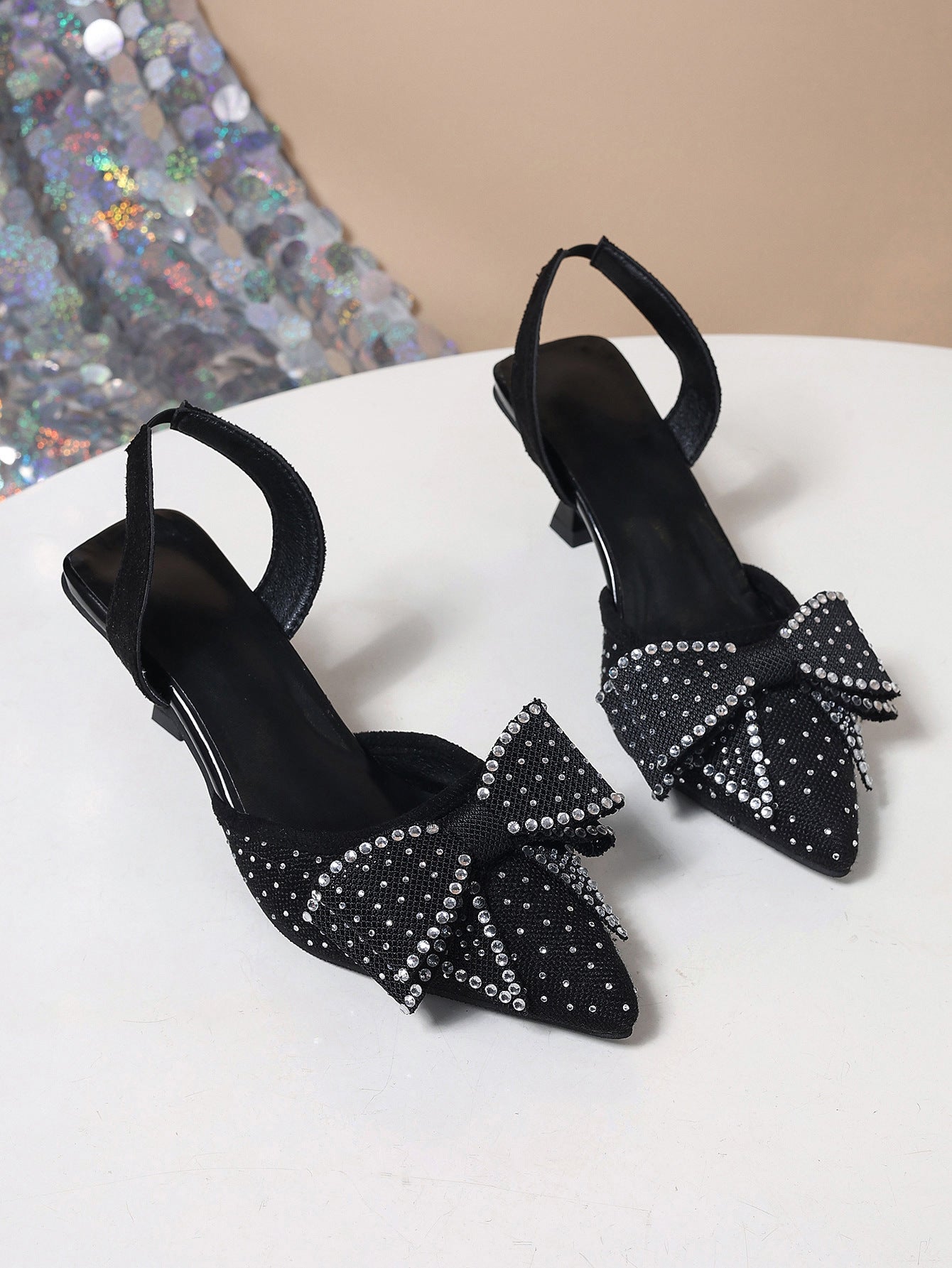 Black slingback heels with rhinestone bowknot detail.