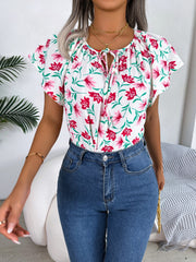 White floral ruffle sleeve tie-neck blouse with pink flowers and green leaves.