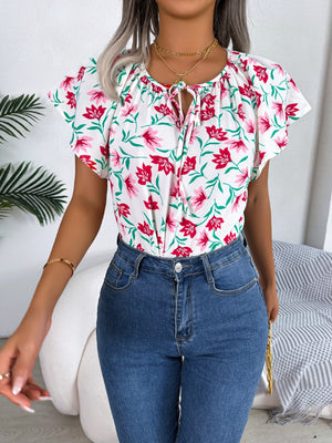 White floral ruffle sleeve tie-neck blouse with pink flowers and green leaves.