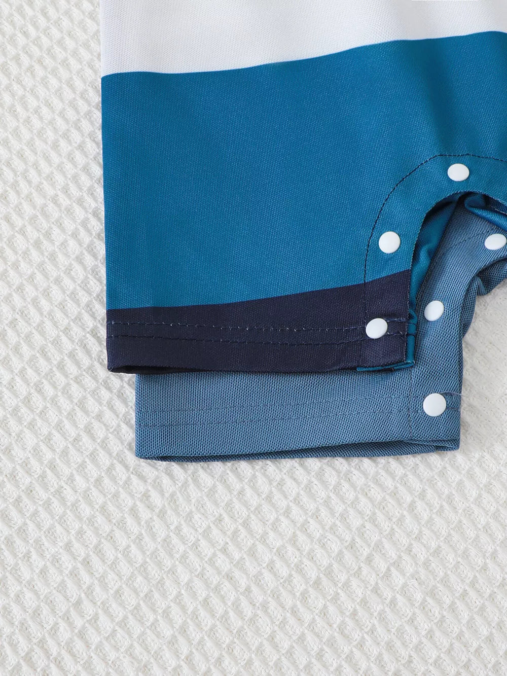 Color block polo romper for kids in blue and white stripes with snap closures.