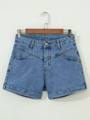 Blue denim shorts with high waist, button fly, angular seams, and cuffed hem.