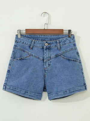 Blue denim shorts with high waist, button fly, angular seams, and cuffed hem.