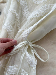 Tiered lace midi dress in ivory with bow detail and textured trim.