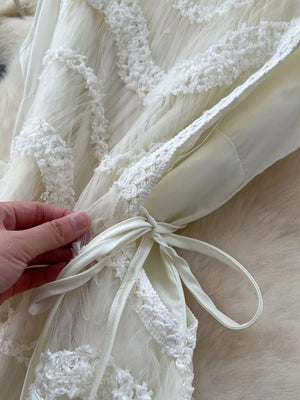 Tiered lace midi dress in ivory with bow detail and textured trim.