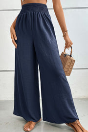 Dark blue textured smocked waist palazzo maternity trousers with wide legs.