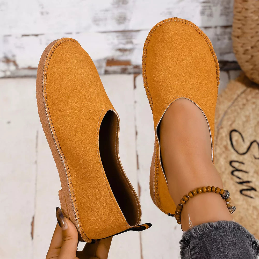 Yellow suede round toe comfort flats with stitched sole detail.