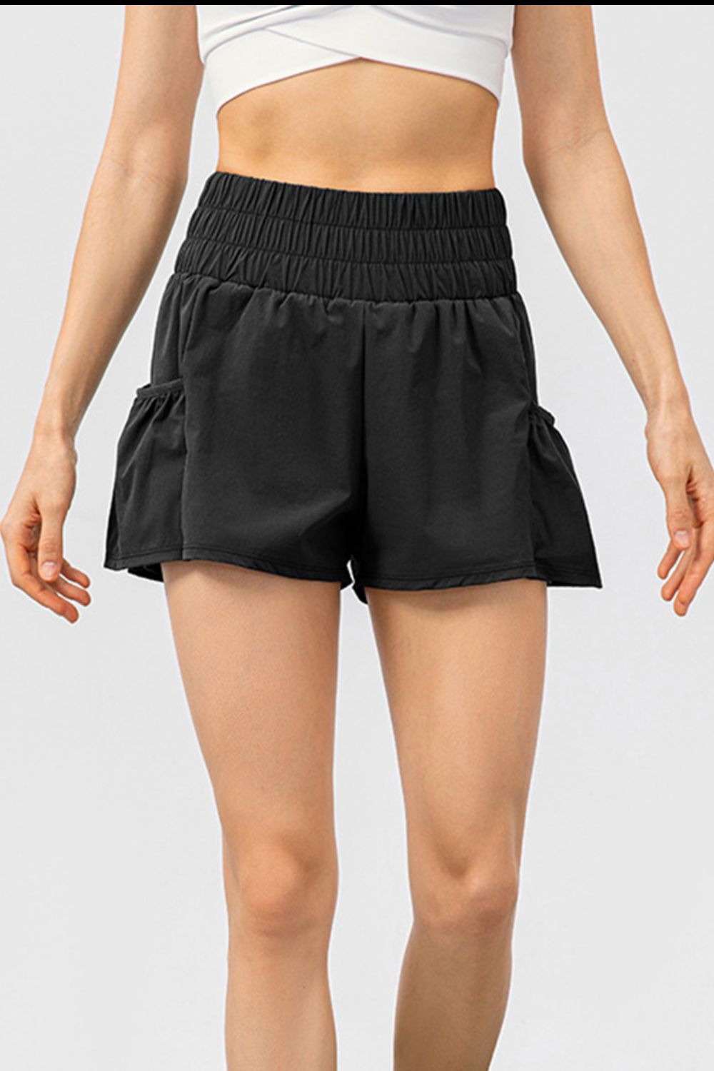 Black active shorts with gathered waistline and ruffled side pockets.
