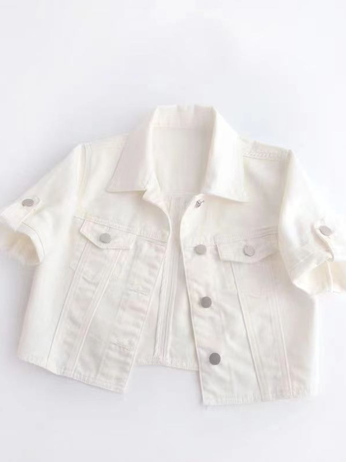 White denim cropped jacket with rolled sleeves and silver buttons