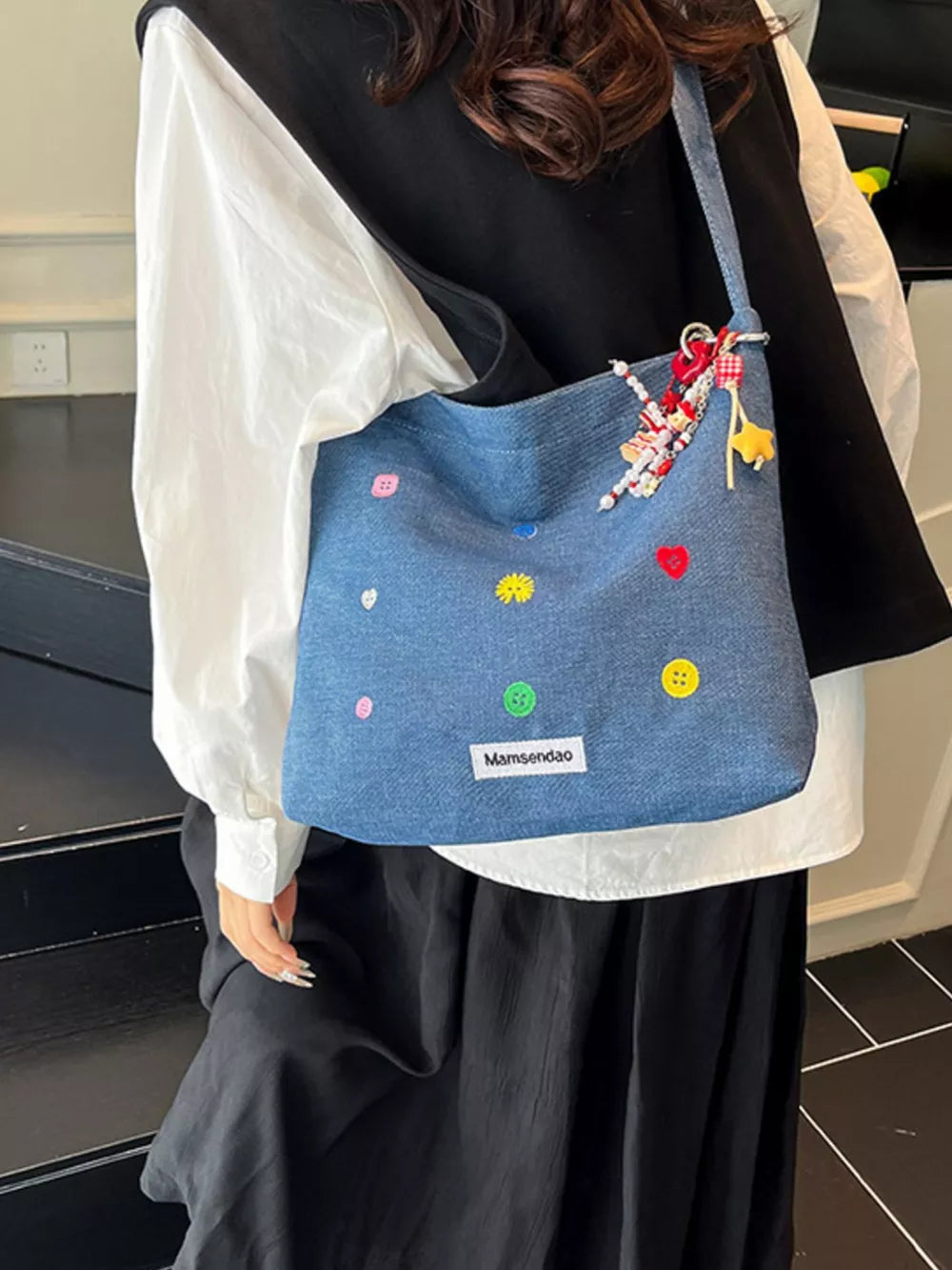 Light blue denim crossbody bag with colorful button appliques and beaded charms.