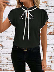 Black maternity blouse with frilled tie-neck and white trim.
