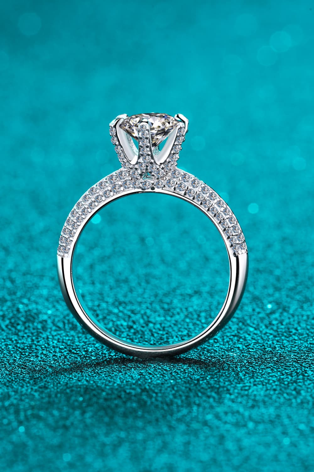 Silver pavé halo moissanite solitaire ring with a round cut center stone.
