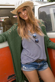 Open-knit Army Green cardigan with slit hem, acrylic material, worn by a model with a striped top and denim shorts.