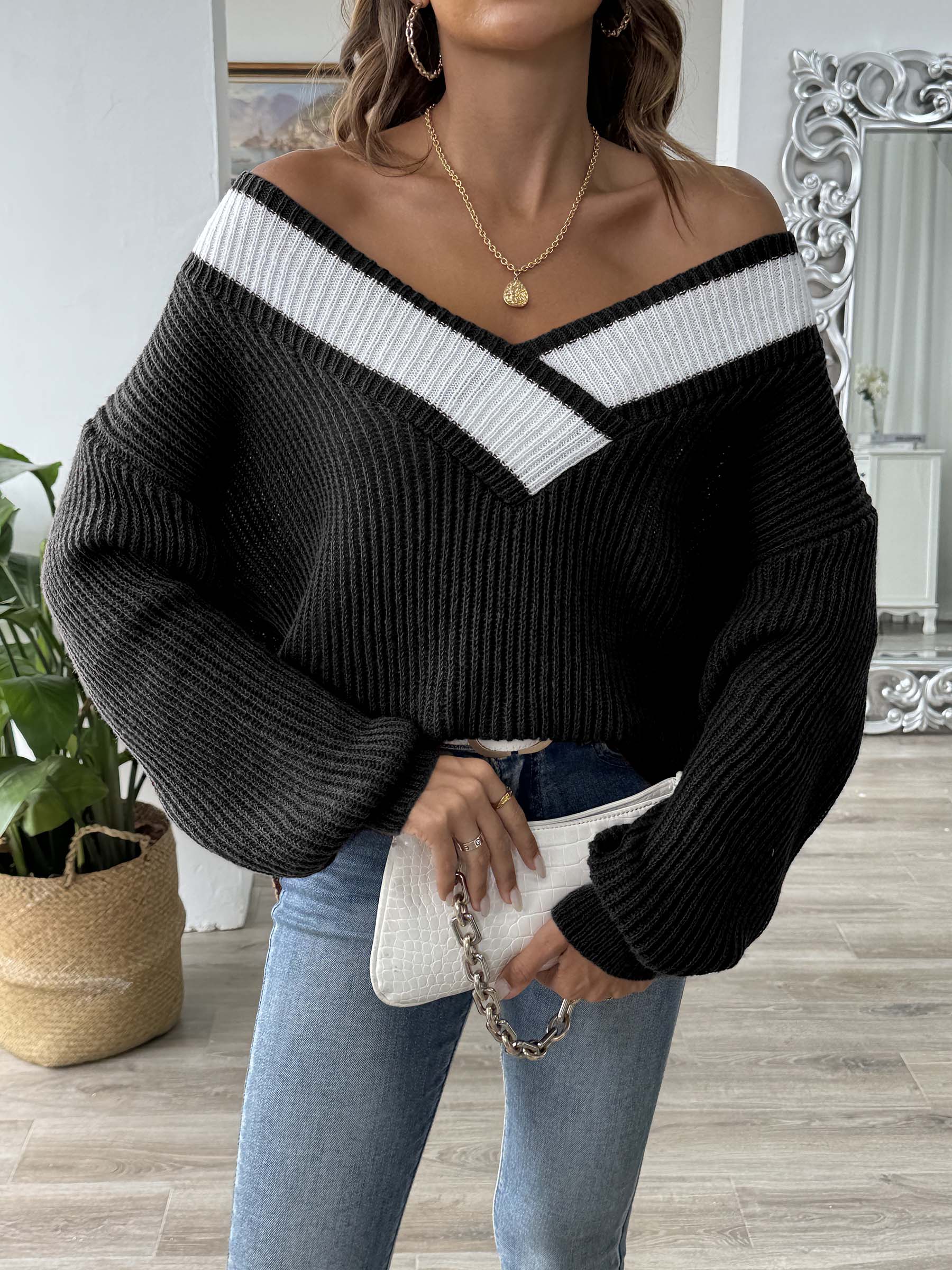 Black off-shoulder knit sweater with white contrast trim and balloon sleeves.