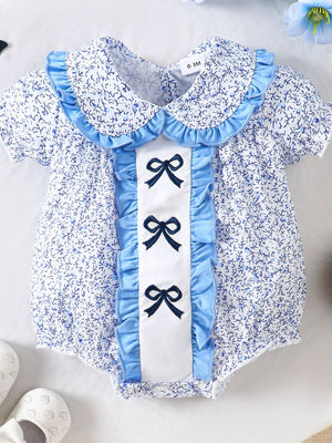 Baby one-piece with floral print, ruffle collar, and three embroidered bows on pastel blue trim.