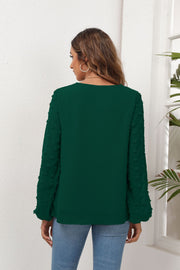 Forest green blouse with pom-pom detail on balloon sleeves and V-neck.