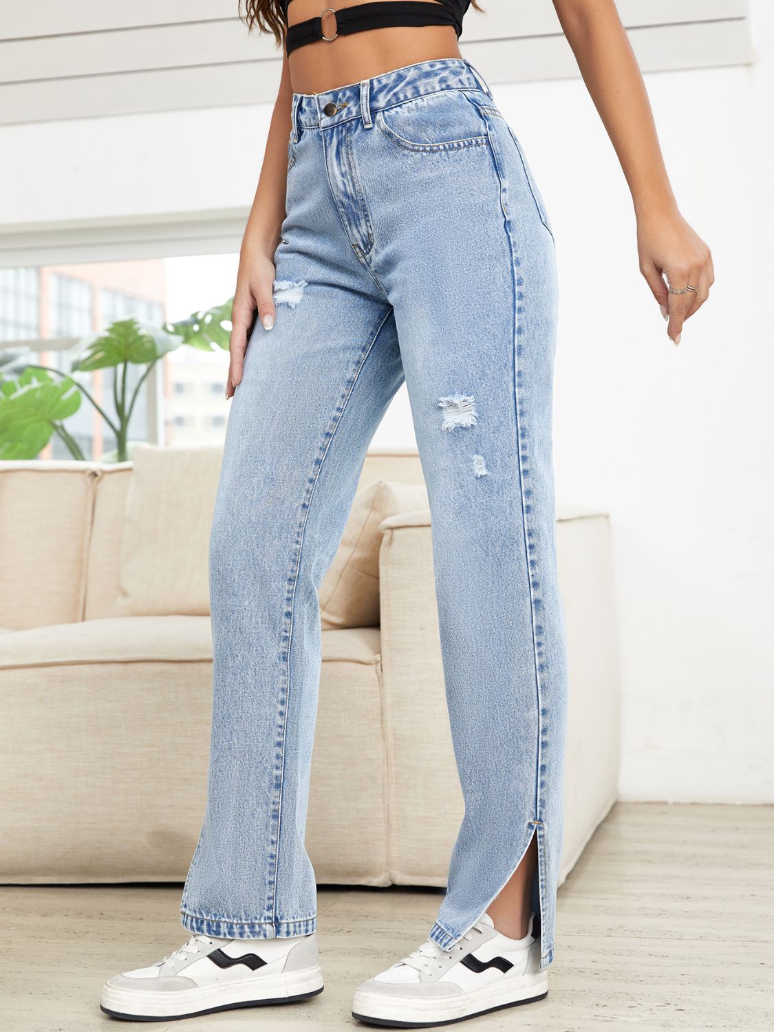 Light wash denim straight leg jeans with distressed details and slit hems.