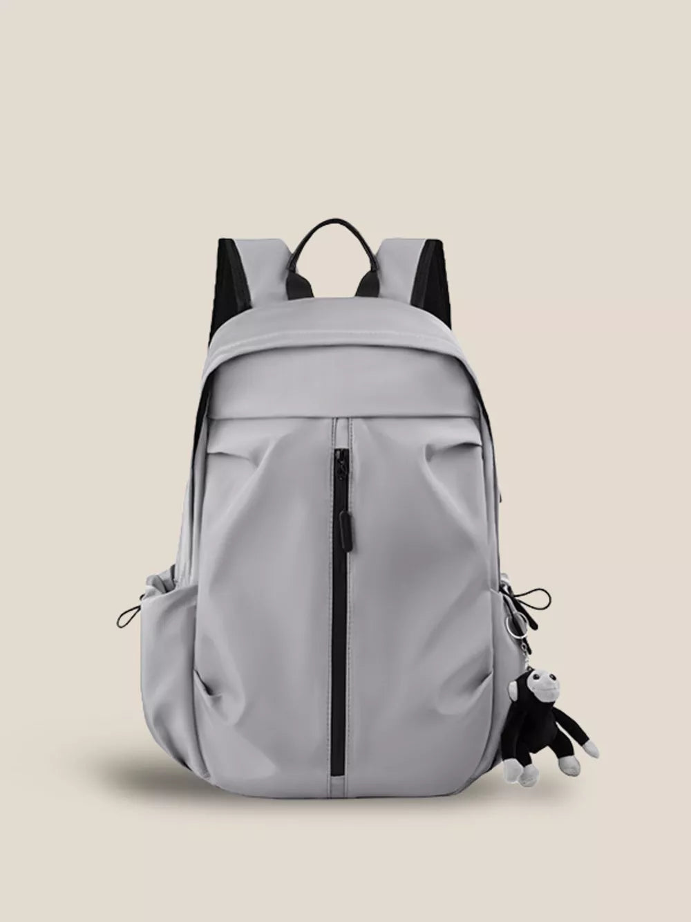 Gray nylon drawstring backpack with monkey keychain and zippered front pocket.