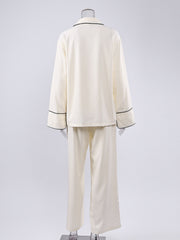 Cream button-up pajama set with black piping on collar, cuffs, and hem.