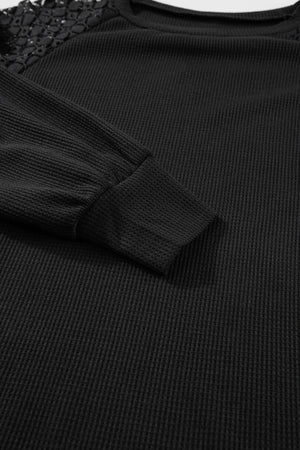 Black waffle knit raglan top with lace yoke detail and cuffed sleeves.