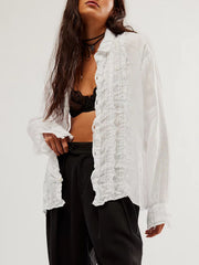 White linen button-down blouse with ruffled front detail and button cuffs.