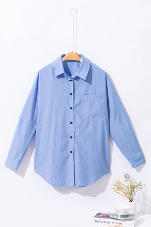 Light blue relaxed fit button-down shirt with vertical stripe texture and chest pocket.