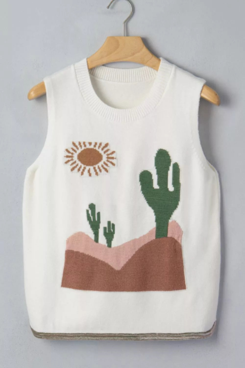 White knit sweater vest with desert cactus and sun graphic, crew neck, sleeveless.