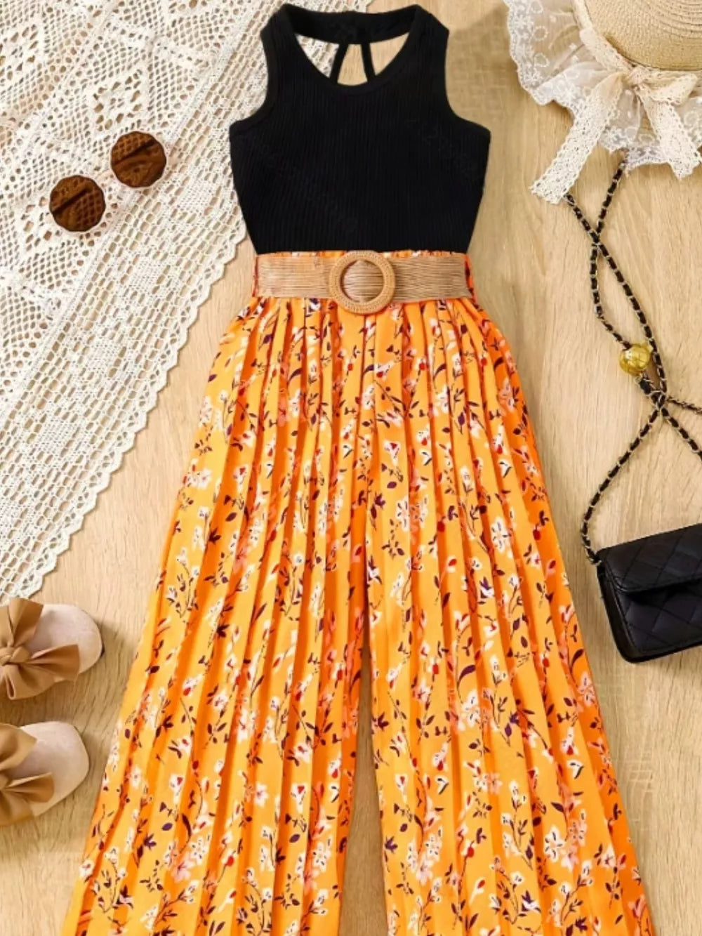 Black ribbed tank top with orange floral print pleated wide-leg pants and a woven belt.