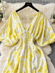 Yellow tropical print smocked wide-leg romper with V-neck and puff sleeves.