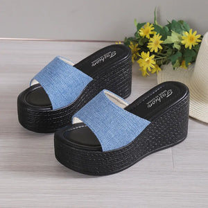 Denim platform wedge slides in light blue with black woven wedge heels.