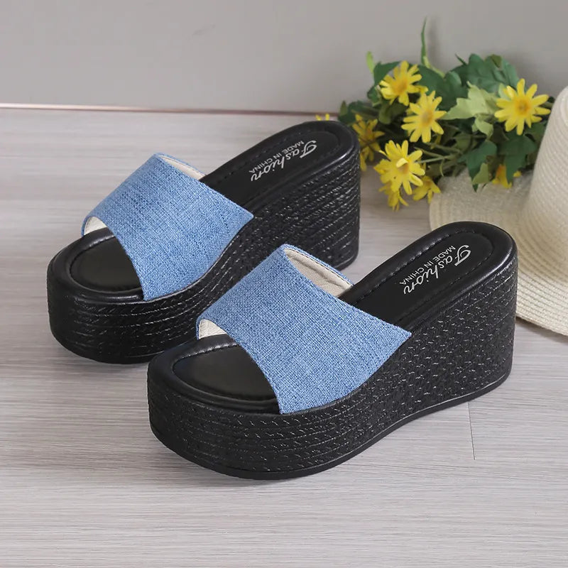 Denim platform wedge slides in light blue with black woven wedge heels.
