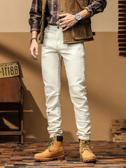 Men's slim-fit cream denim jeans with moto-style knee panels and zipper details.
