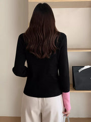 Black ribbed cardigan with pink contrast sleeve detail.