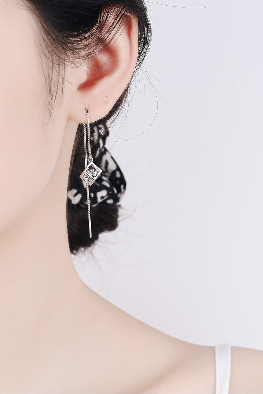 Silver geometric cube threader earrings with clear gems on a chain.