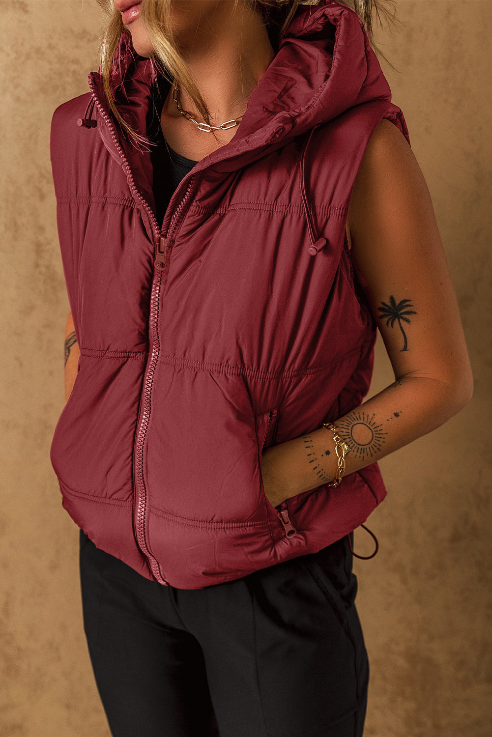 Burgundy quilted hooded puffer vest with drawcord detail and zip pockets.