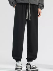 Men's black loose fit sweatpants with white drawstring and cuffed ankles.