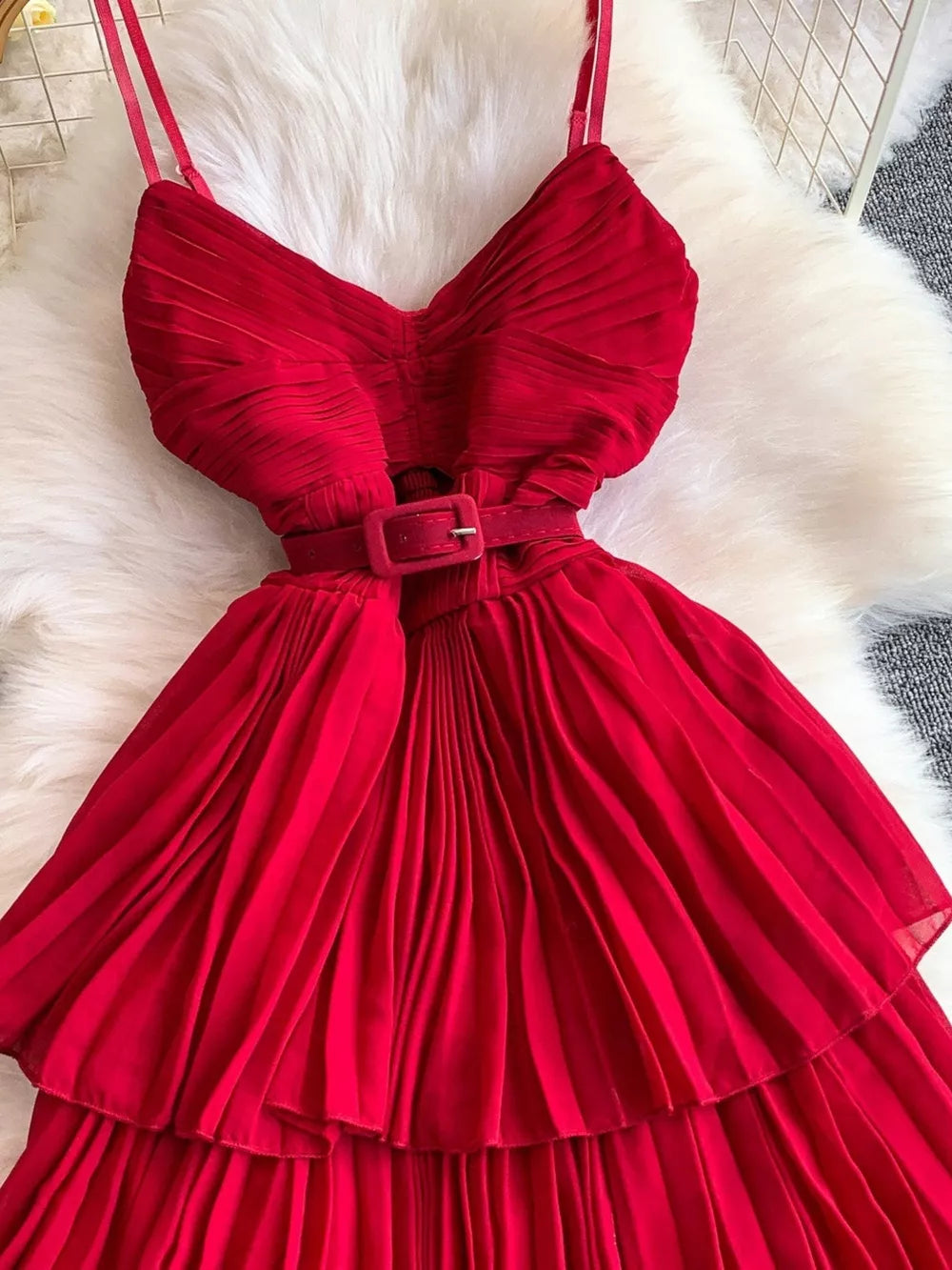 Red belted pleated midi dress with spaghetti straps and a buckle.