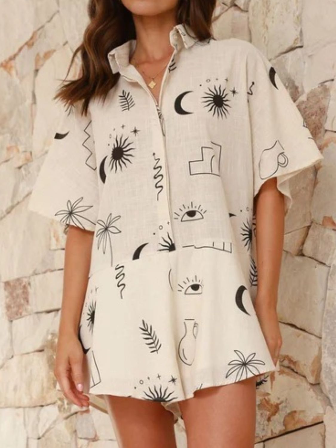 Beige linen romper with celestial print, buttoned collar, and flared hem.