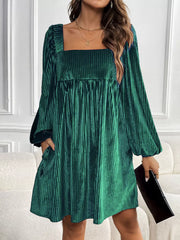 Chic dark green velvet mini dress with square neckline and pleated detail.