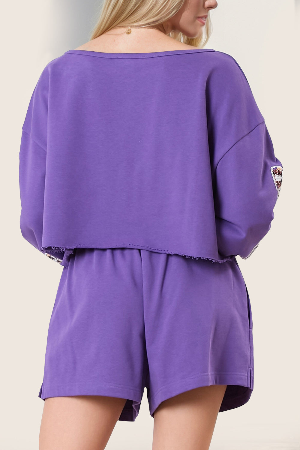 Violet cropped sweatshirt set with raw hem and embroidered sleeve detail.