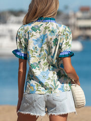 Floral frilled blouse with blue and green detail, short sleeves, and ruffled neckline.