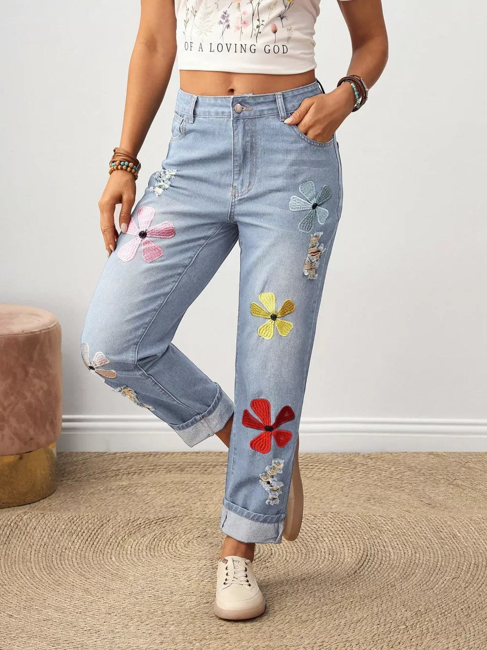 Light wash denim jeans with embroidered floral accents and distressed details.