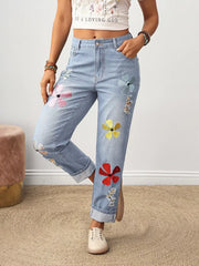 Light wash denim jeans with embroidered floral accents and distressed details.