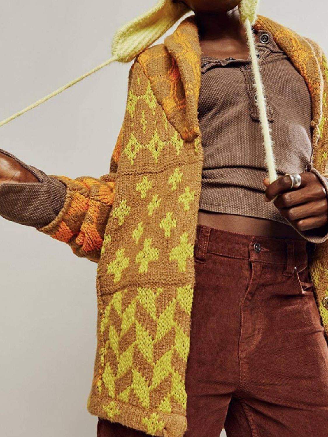 Geometric patchwork knit cardigan in brown with yellow pattern, featuring a buttoned front and long sleeves.
