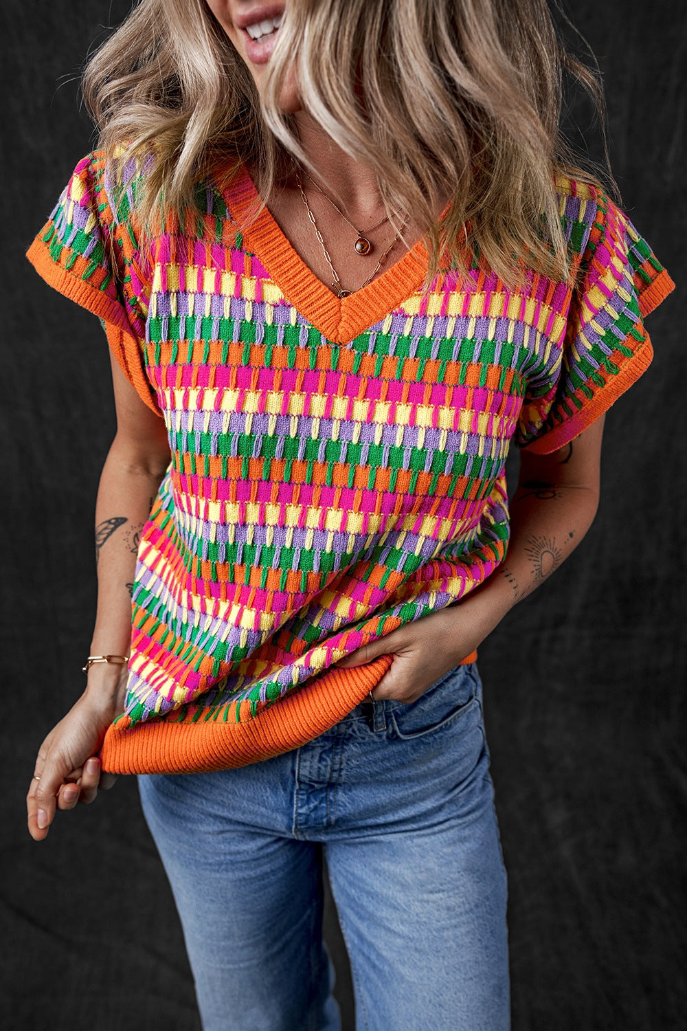Geometric knit flutter sleeve top with V-neck in multicolor pattern and orange trim.