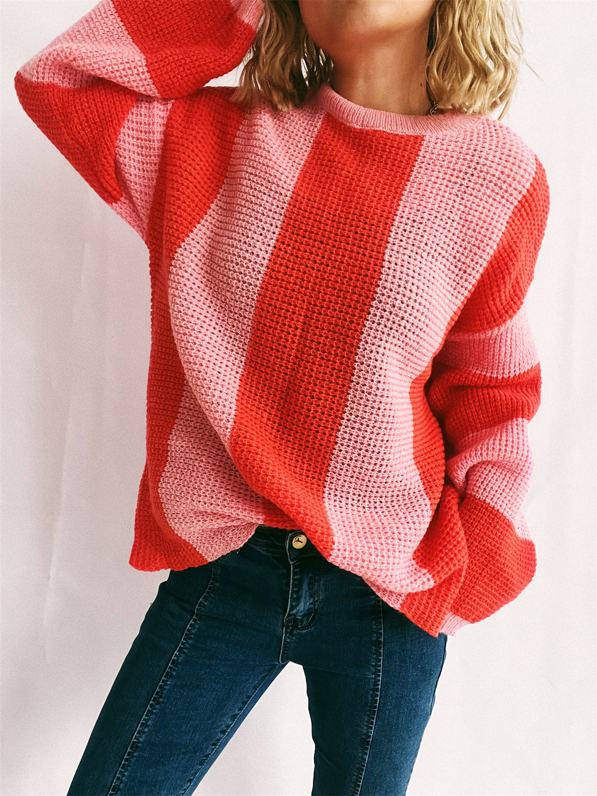Vertical stripe waffle knit sweater in orange-red and pink with crewneck and long sleeves.