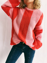 Vertical stripe waffle knit sweater in orange-red and pink with crewneck and long sleeves.