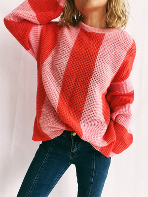 Vertical stripe waffle knit sweater in orange-red and pink with crewneck and long sleeves.
