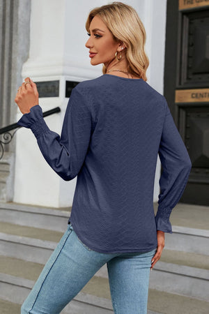 Dark blue textured V-neck blouse with smocked cuffs and long sleeves.